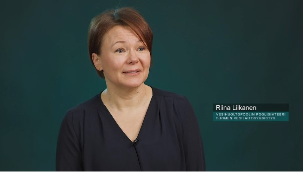 Kuvakaappaus videolta, tumman vihreää taustaa vasten Riina Liikanen poolisihteeri