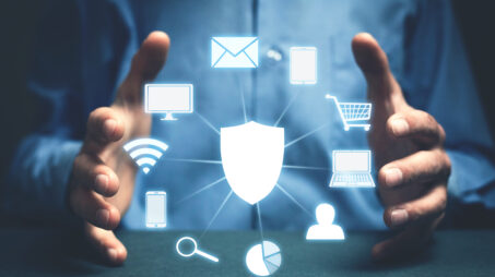 Kauluspaitainen henkilö pitää käsiään eteenpäin työnnettynä. Käsien välissä on kuvanmuokkauksella lisätty erilaisia tietoturvaan ja internetiin liittyviä kuvakkeita.